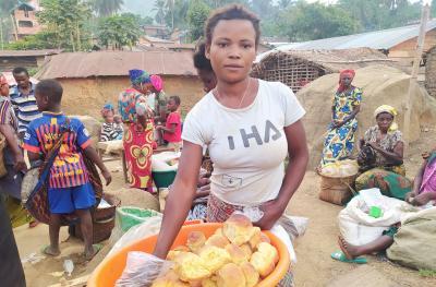 A woman who graduated from the DRC program in a busy street holds a basket of bread