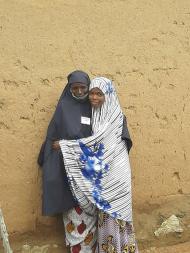 Aishatu, a participant of Women for Women International, stands hugging her daughter