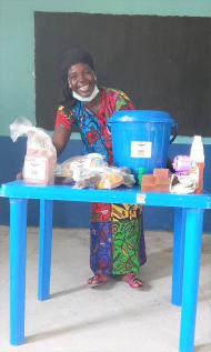 Saratu, a participant from Nigeria, sits at a blue table with her food package and hygiene supplies