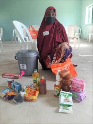Hassana standing among supplies to help her and her family survive the pandemic