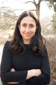 Kara Alaimo headshot - Kara outside smiles confidently at the camera, with her arms folded