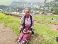 Zawadi from Rubaya, North Kivu - Democratic Republic of the Congo - looks at the camera while sitting on a green field