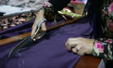 Womans hand cutting cloth with scissors 