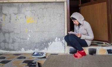 Woman sitting in a doorway writing in a notebook