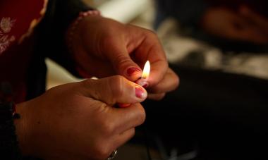 A woman from the Iraq program holds a small flame in her hands. Credit: Women for Women International