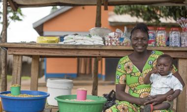 Josephine, a participant in South Sudan, sits with her son in front of her business. Photo credit: Charles Atiki Lomodong