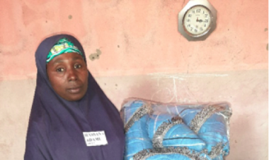 Hassana, a program participant, holding the bags she made to sell