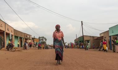 A woman stands tall in the middle of a road in Rwanda, centered in the frame; Photo Credit: GiveWith