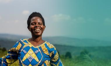 hero smiling woman from rwanda with mountains and blue sky
