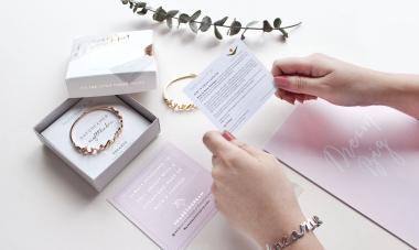 hands holding gift set with bracelet and card
