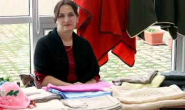 woman sitting behind table with piles of clothes