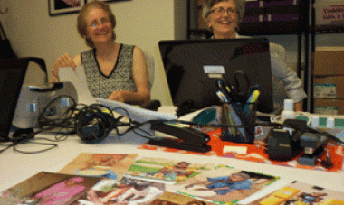 two women with a computer smiling 