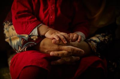 Woman has arms wrapped around child in her lap